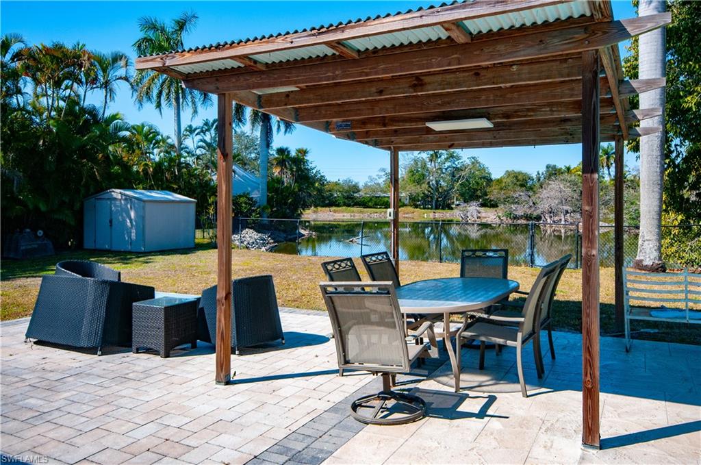 View of patio featuring a storage unit, a water view, and outdoor dining space