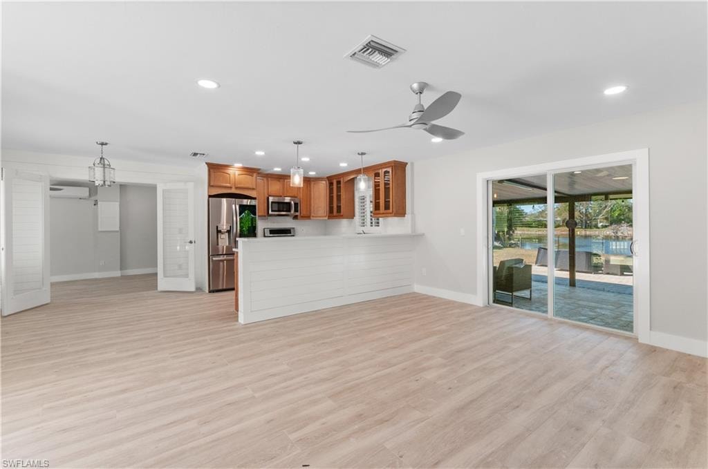 Unfurnished living room with light wood-type flooring, ceiling fan, and hanging lights