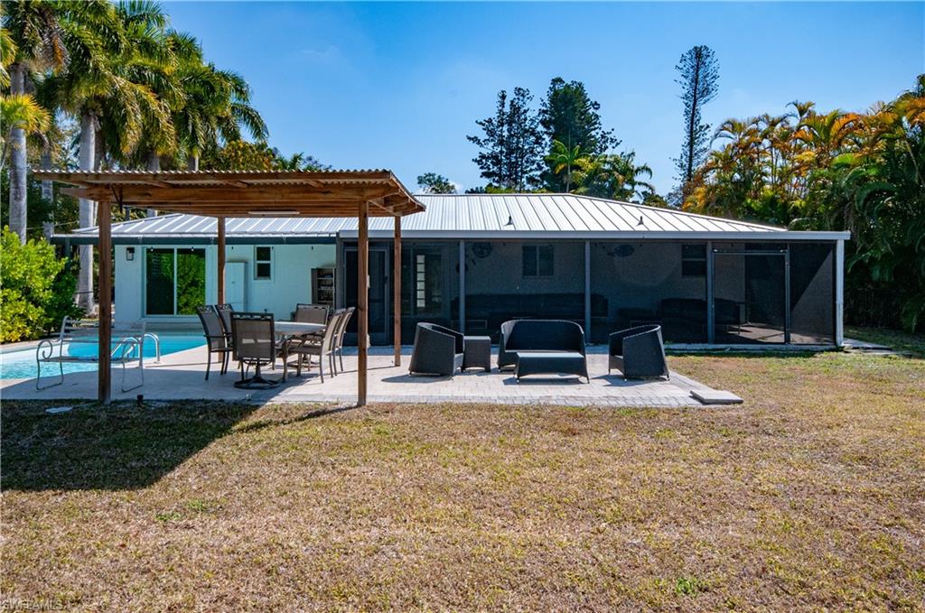 Rear view of house with a pergola, a yard, a patio area, an outdoor pool, and a metal roof
