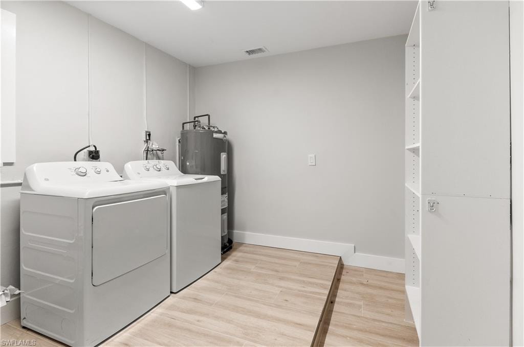 Laundry room AND STORAGE  with light wood-style flooring, washer and dryer, and water heater