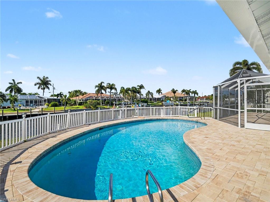 Open air pool with new deck pavers and beautiful views of the water, palm trees and waterfront homes