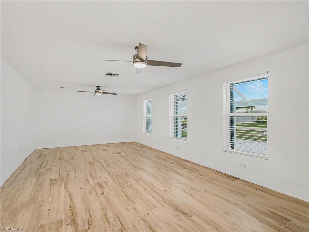 Large living room with multiple windows and ceiling fans, overlooking the front courtyard