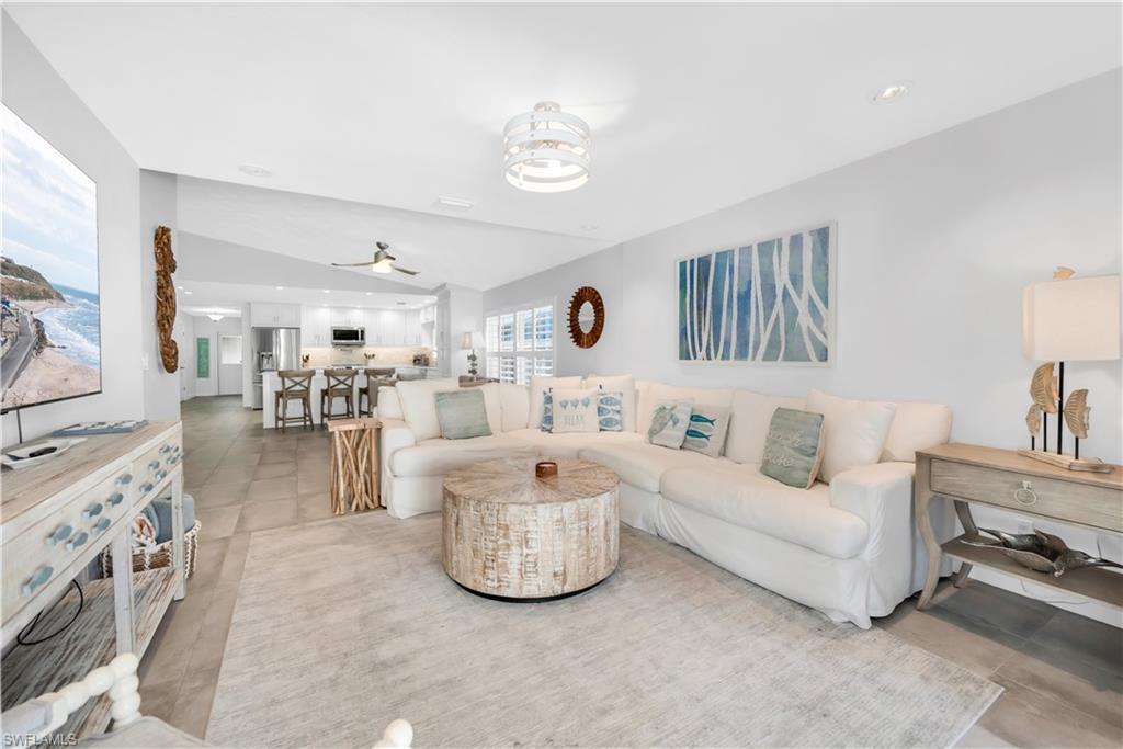 Living room with a ceiling fan, lofted ceiling, and light tile patterned floors