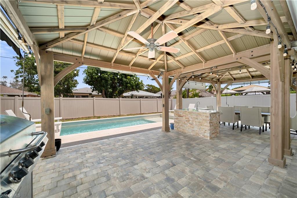 Fenced backyard featuring a gazebo, ceiling fan, a patio, and grilling area