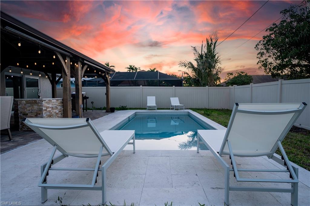 Pool at dusk with a patio and a fenced backyard