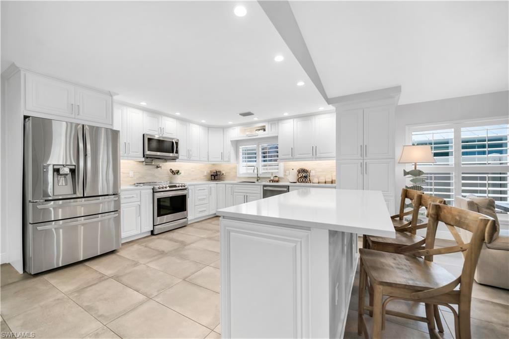 Kitchen with stainless steel appliances, light countertops, backsplash, recessed lighting, and a sink