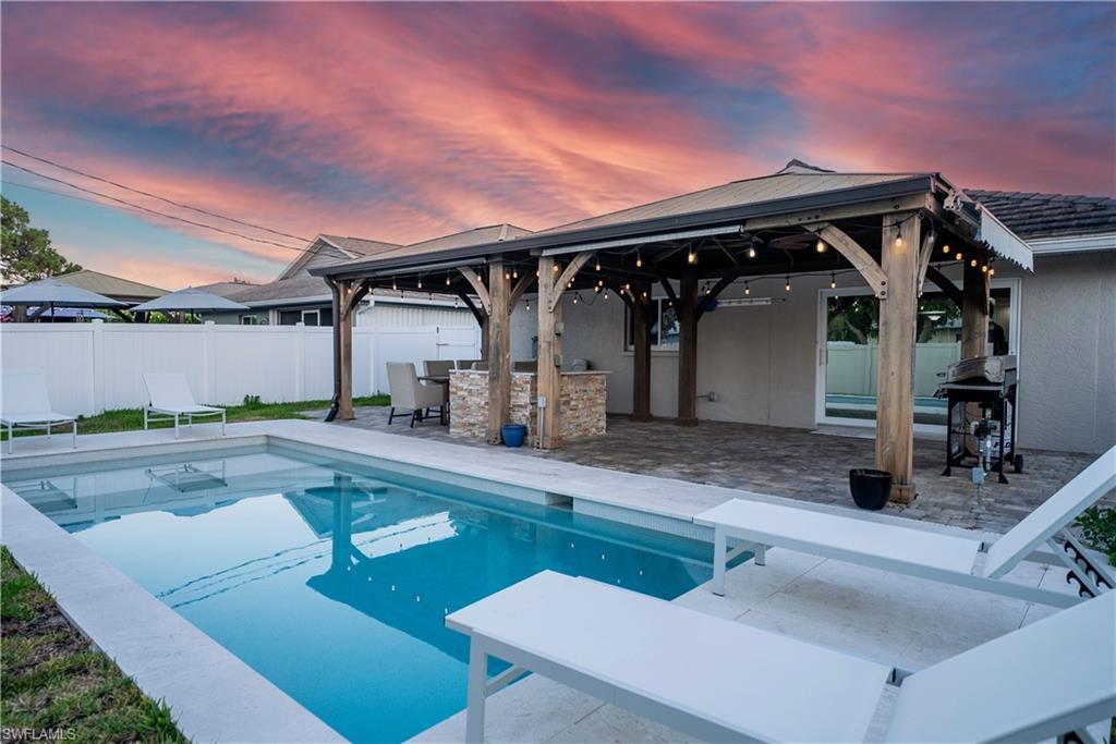Pool at dusk featuring a gazebo, a fenced backyard, grilling area, and a patio