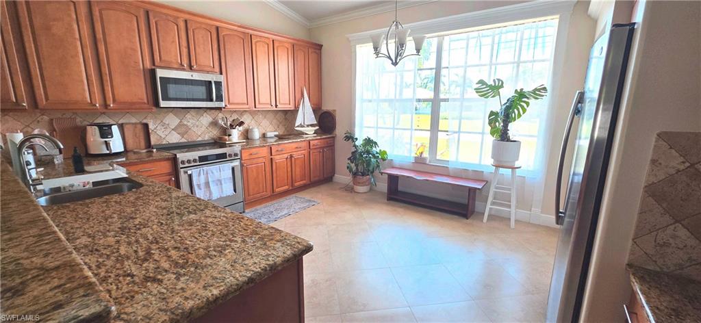 Kitchen featuring wood cabinetry, stainless steel appliances, granite countertops, and a tiled backsplash
