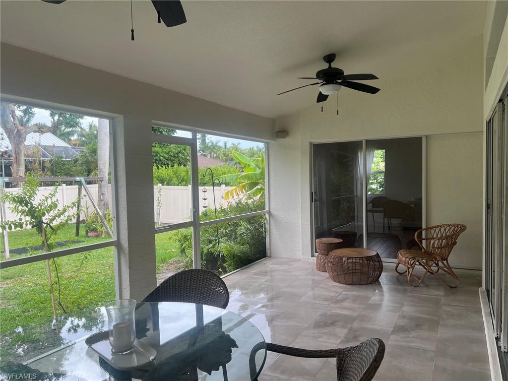 Screened-in patio featuring light-toned tile flooring, dual ceiling fans, and sliding glass door access to interior spaces