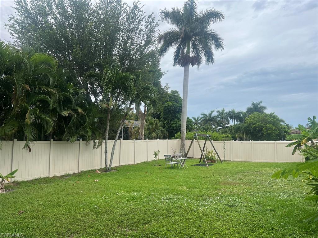 Expansive green lawn with mature palm trees and tropical foliage