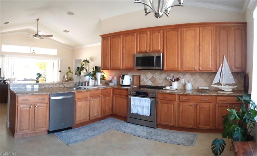Kitchen featuring wood cabinetry, stainless steel appliances, granite-finish countertops, and a tiled backsplash