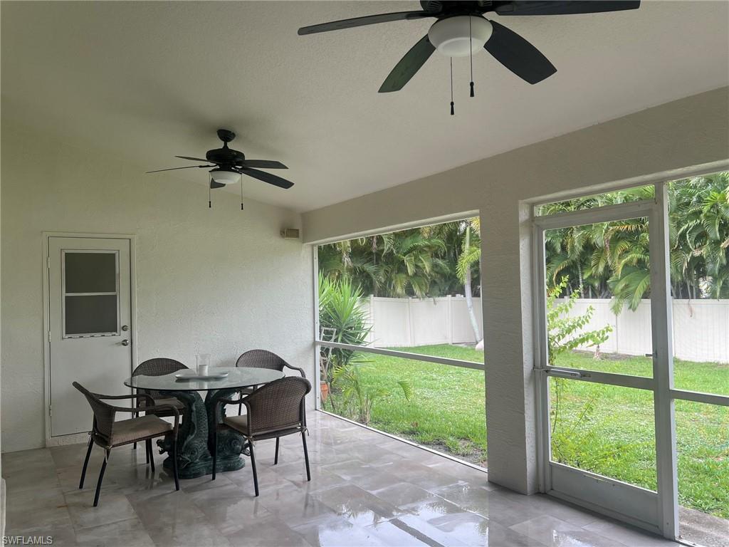 Expansive screened patio featuring two ceiling fans, a white exterior door with a window, a screened door to the yard, and tile flooring