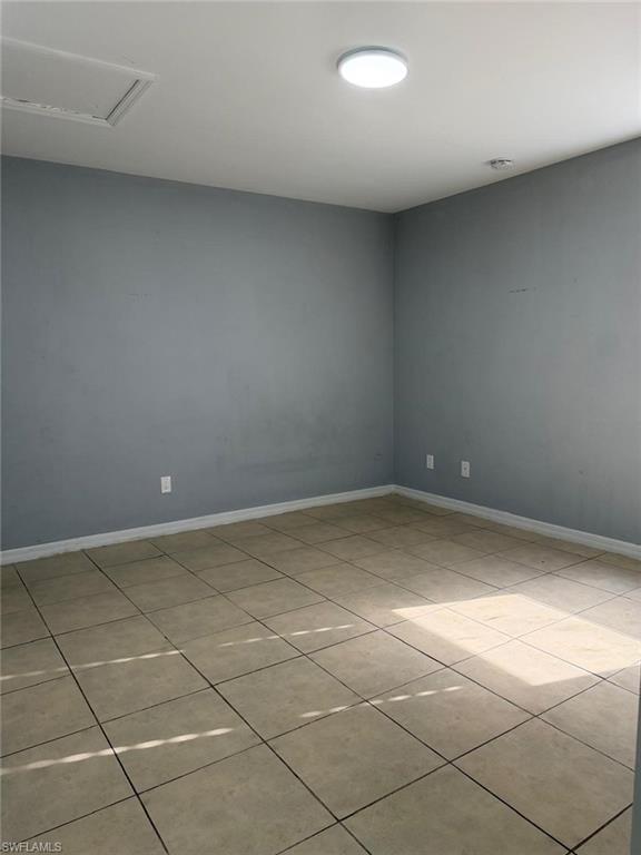 Room featuring light beige tile flooring, light blue-grey painted walls, and white baseboards