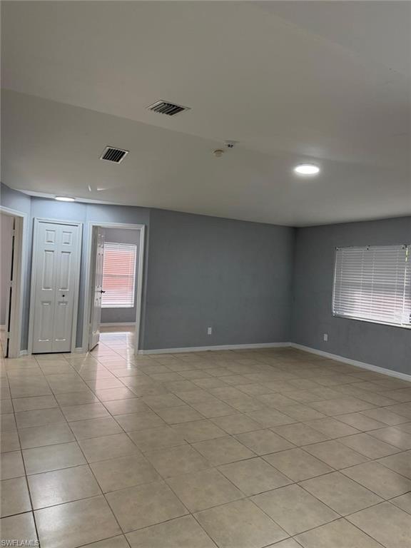 Spacious living area featuring neutral tile flooring, light gray wall paint, and white trim
