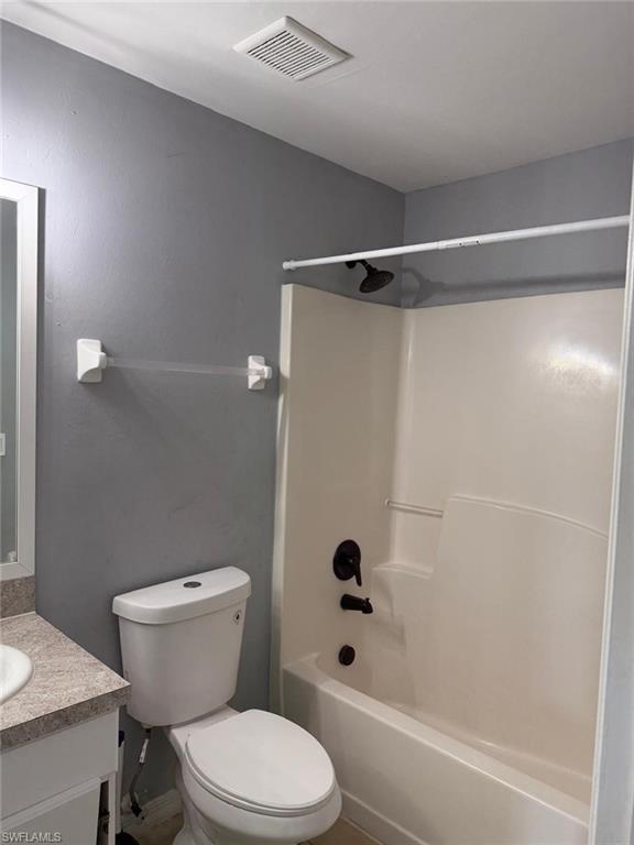 Bathroom featuring a white toilet, white tub-shower combination, and dark bronze bath fixtures