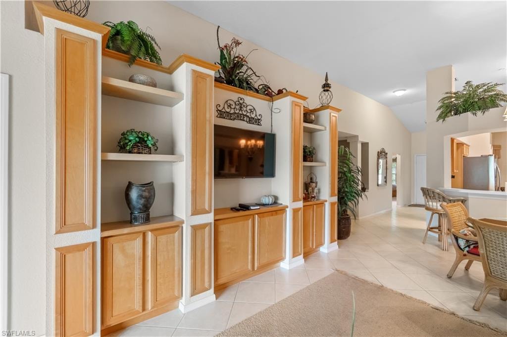 Hall with vaulted ceiling, built in features, and light tile patterned floors