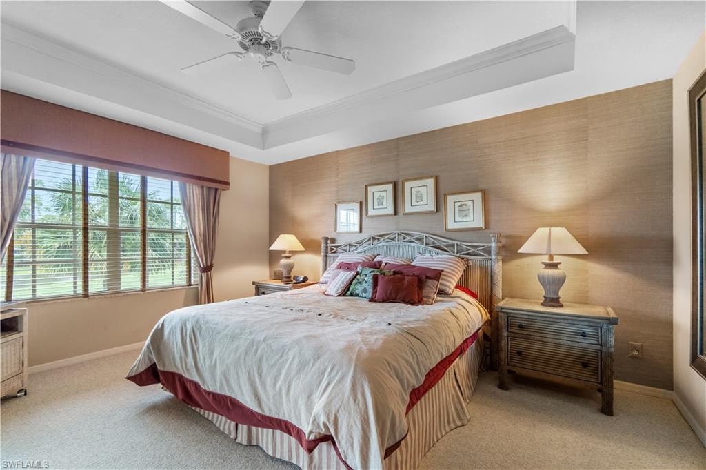 Bedroom with crown molding, a tray ceiling, light colored carpet, and ceiling fan