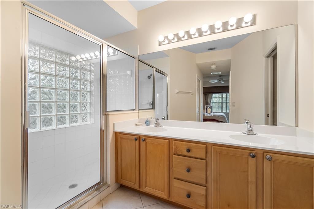 Bathroom with ceiling fan, tile patterned flooring, walk in shower, and double vanity
