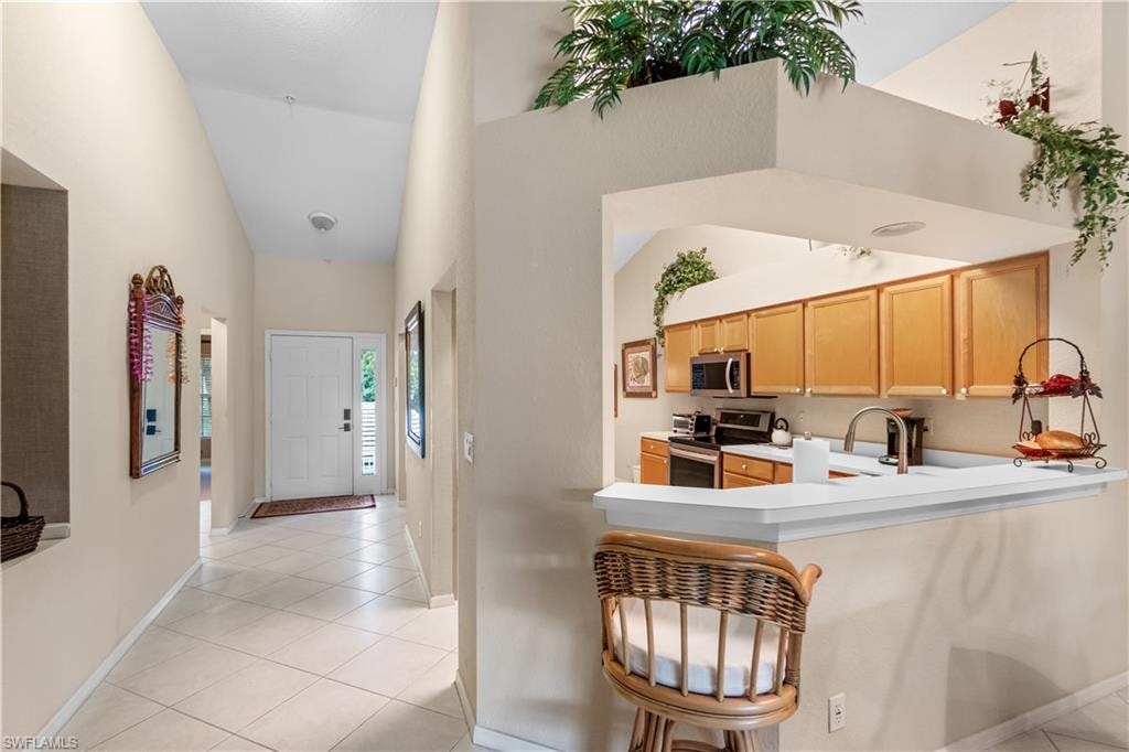 Kitchen with sink, light tile patterned floors, light brown cabinets, and stainless steel appliances