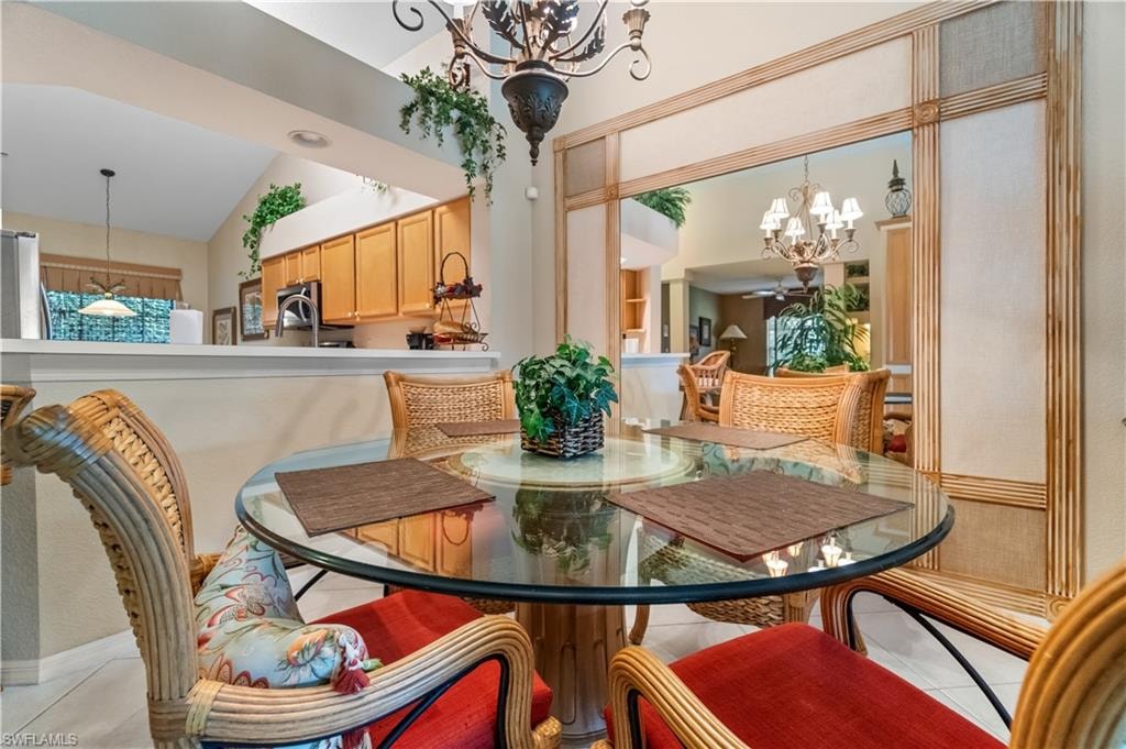 Dining room featuring a notable chandelier, vaulted ceiling, and light tile patterned floors