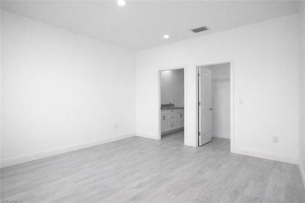 Spacious interior with neutral white walls, recessed ceiling lighting, light wood-finish flooring, and white baseboards