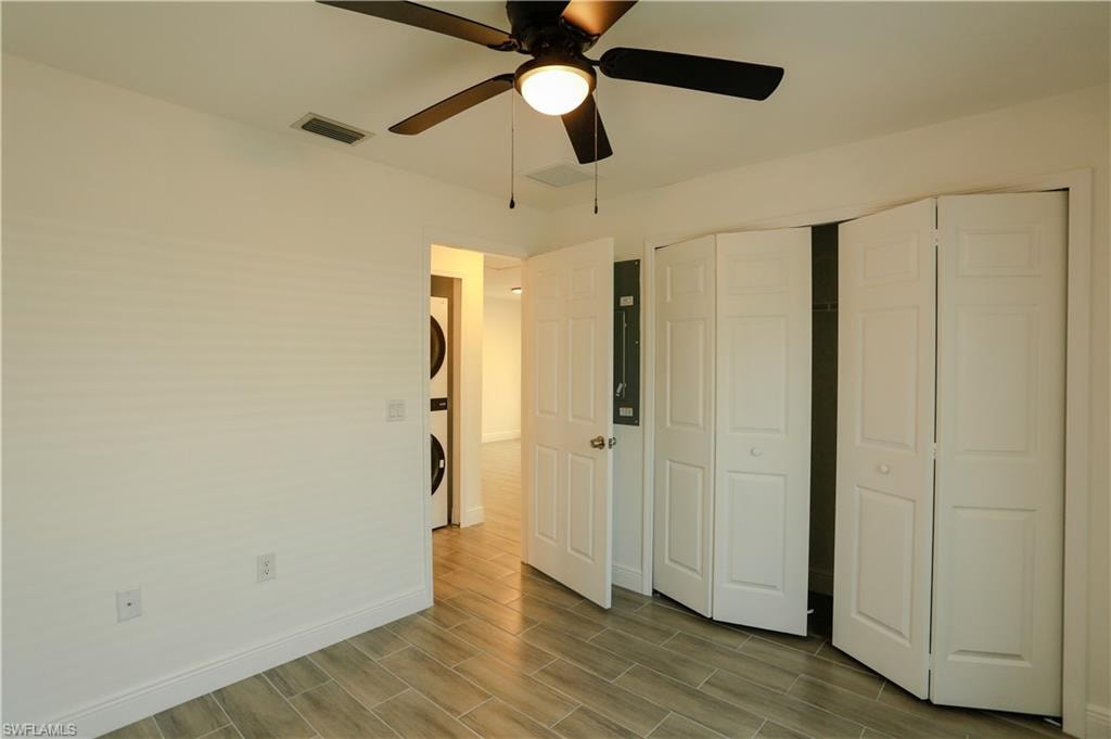 Interior room featuring light-toned walls, a black ceiling fan, and light wood-look tile flooring