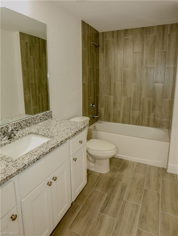 Bathroom featuring a full vanity with an integrated sink, granite-style countertop, and white cabinetry with brass-tone hardware
