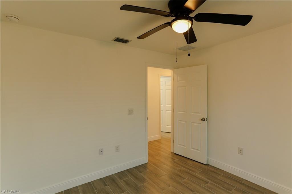 Interior space featuring wood-finish flooring, white walls, and a ceiling fan with integrated lighting