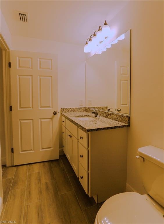 Bathroom featuring a white vanity with multiple drawers and cabinets, a speckled countertop, an undermount sink, and a large wall-mounted mirror