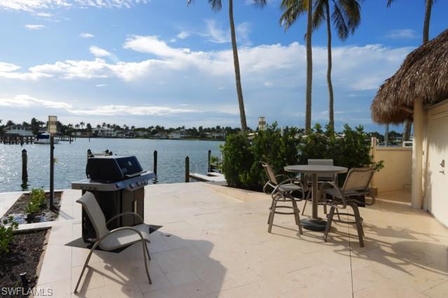 View of patio with a dock, a water view, and area for grilling