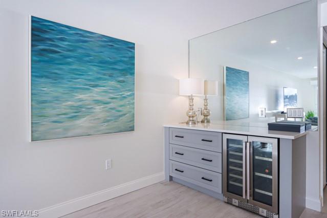 Indoor dry bar featuring wine cooler, light wood finished floors, and recessed lighting