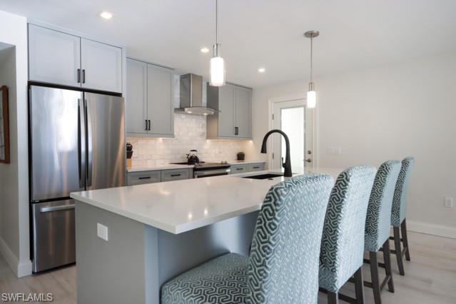 Kitchen with freestanding refrigerator, light wood-style flooring, decorative backsplash, light countertops, and recessed lighting