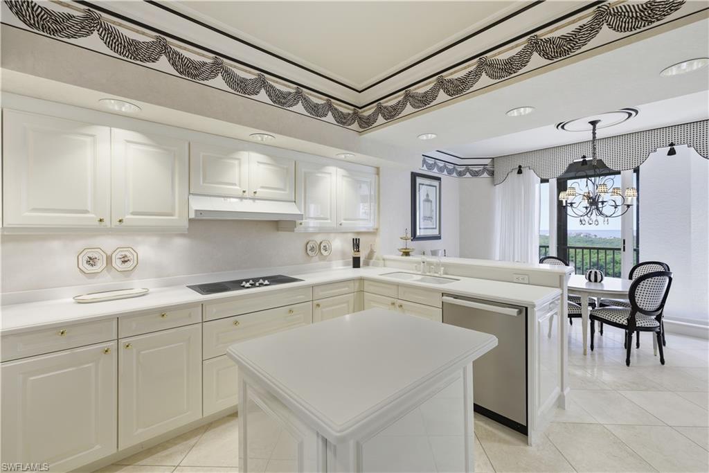 Kitchen with a center island, a chandelier, a peninsula, dishwasher, and light countertops