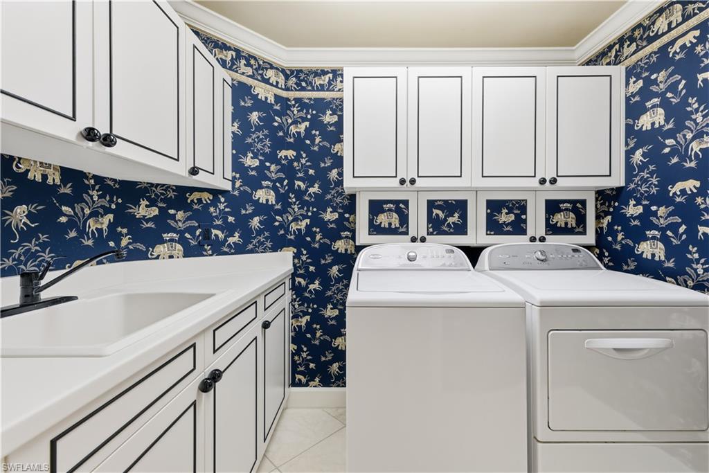 Laundry room with wallpapered walls, independent washer and dryer, light tile patterned floors, cabinet space, and ornamental molding