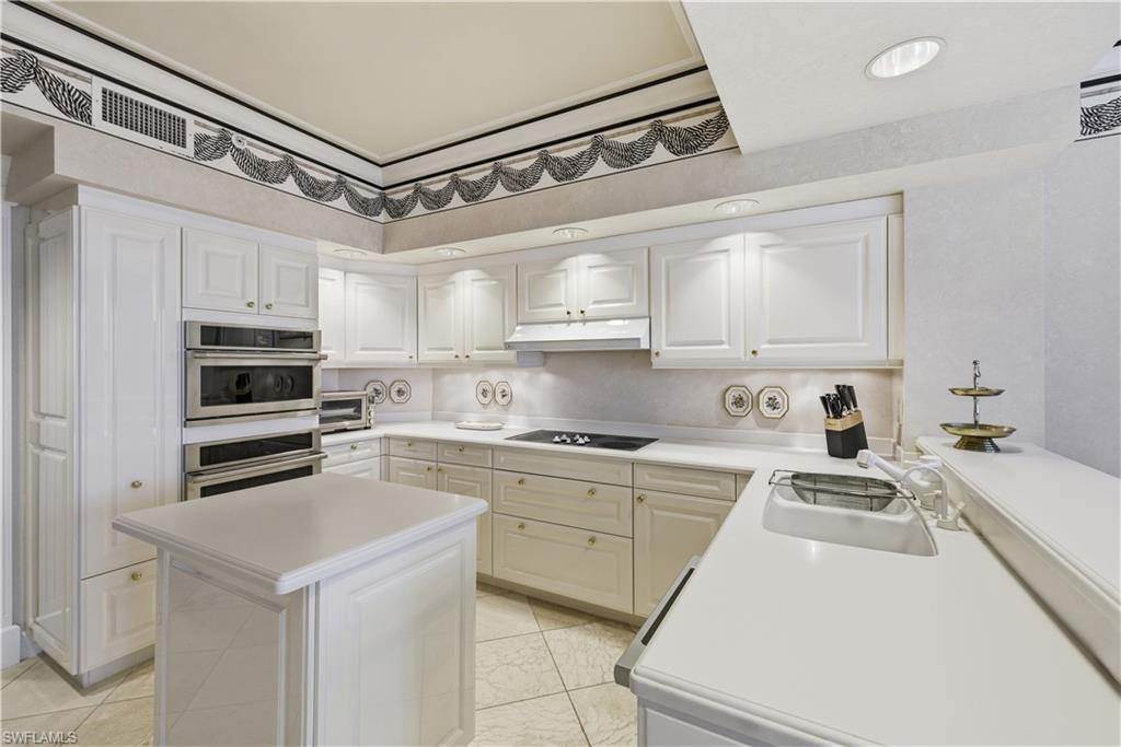 Kitchen with light countertops, double oven, and white cabinetry