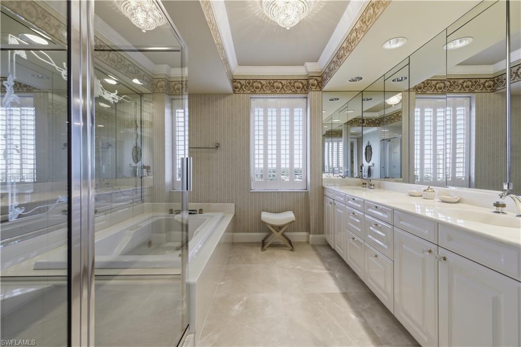Bathroom with wallpapered walls, a bath, double vanity, ornamental molding, and a shower stall