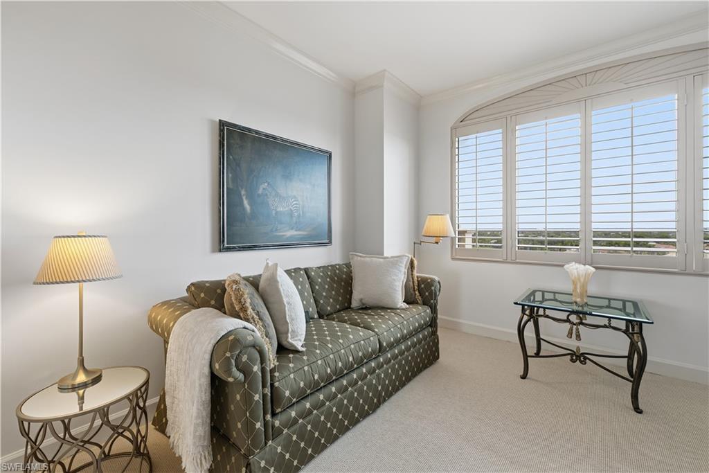 Carpeted living area with baseboards and crown molding
