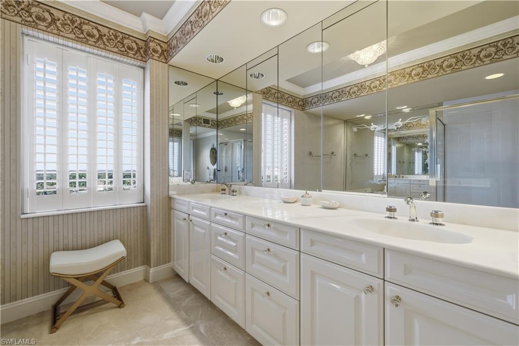 Full bath with double vanity, plenty of natural light, ornamental molding, a shower stall, and light tile patterned flooring