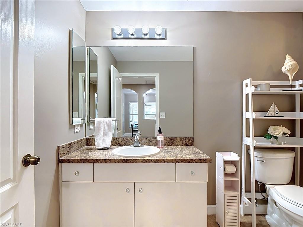 Bathroom vanity featuring a white undermount sink, a brown speckled countertop, and white cabinetry with clear knobs