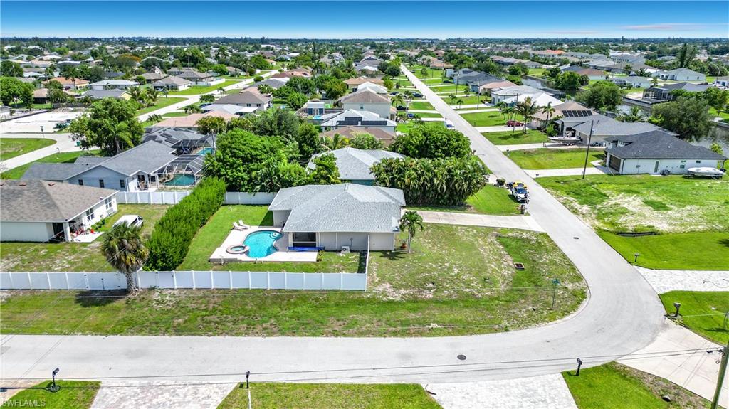 Single-story residence featuring a private swimming pool with a paved patio, a white privacy fence, and mature landscaping
