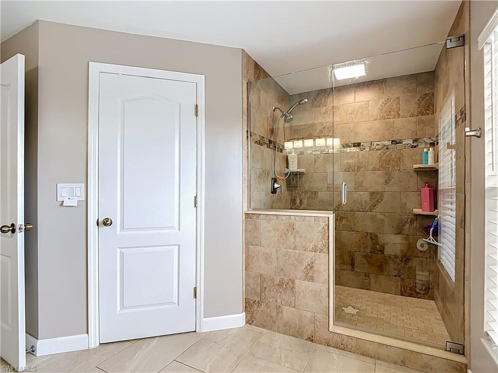 Tiled walk-in shower with a glass enclosure, integrated shelving, and a mosaic floor