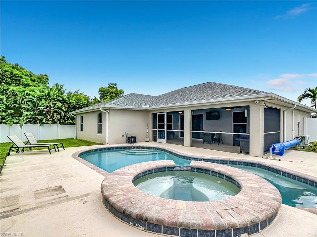 Outdoor living area featuring a freeform swimming pool with integrated spa and a screened-in patio