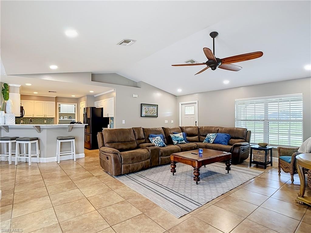 Open concept living area featuring tile flooring, vaulted ceilings, recessed lighting, and a dark wood-finish ceiling fan