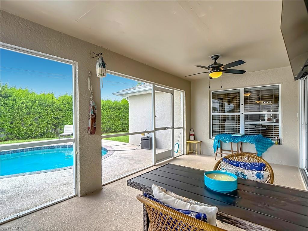 Screened lanai featuring a ceiling fan, textured concrete flooring, and direct access to a private swimming pool with an integrated spa