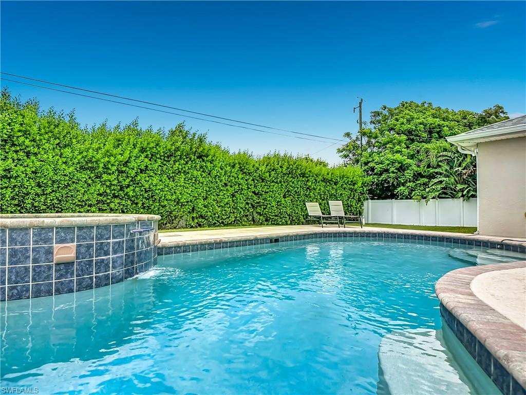 In-ground swimming pool with an integrated spa, featuring blue tile accents and a stone coping