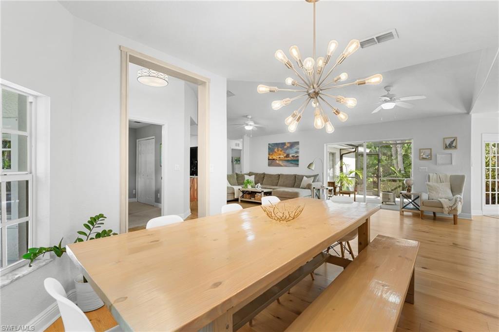 Dining area featuring wood-finish flooring, a contemporary sputnik chandelier, and a large wood table with bench seating