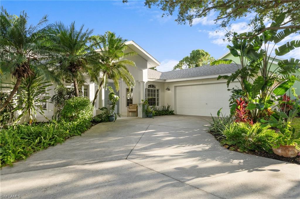 Two-car garage, mature tropical landscaping,  covered entry, and an arched window accent
