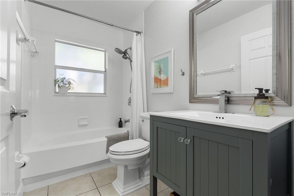Modern bathroom featuring a dark grey vanity with a white countertop and integrated sink, chrome faucet, and a large framed mirror