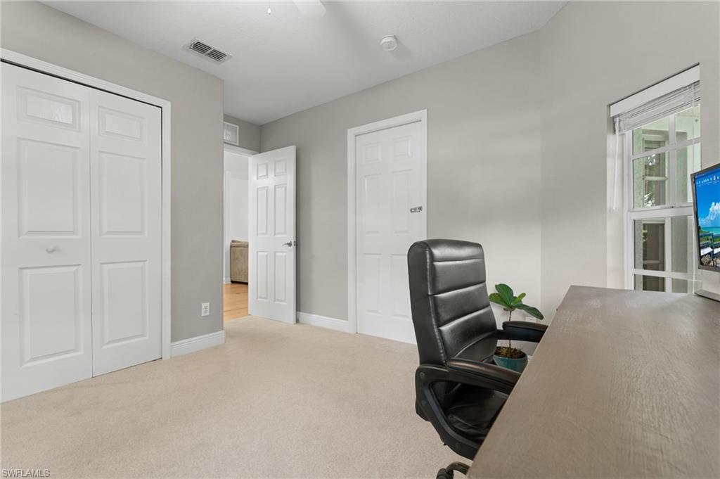 Carpeted room featuring light gray walls, white baseboards, and a white ceiling fan