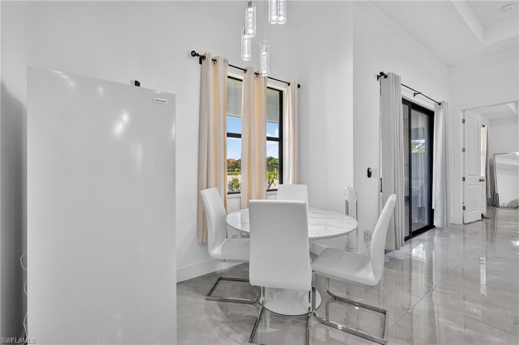 Bright dining area featuring a modern chandelier, tall windows, and tile flooring